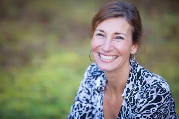 Nicole Apelian smiling warmly, with a backdrop of nature, reflecting her connection to herbal remedies and natural healing practices.